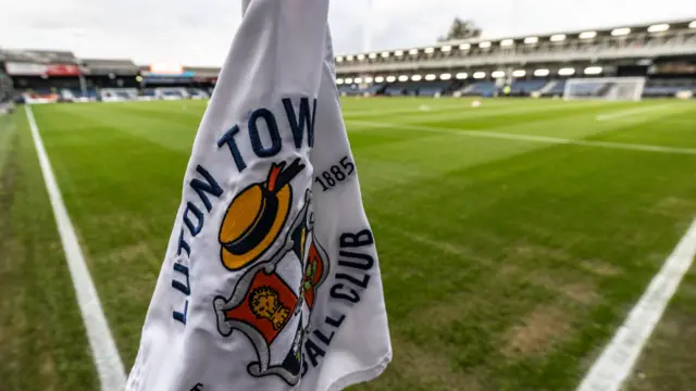 A corner flag with the Luton crest stands on the pitch at Kenilworth Road.