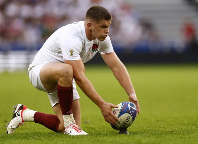 Owen Farrell tees up his ball on a tee