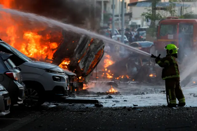 An emergency personnel works to extinguish fire after rockets were launched from the Gaza Strip