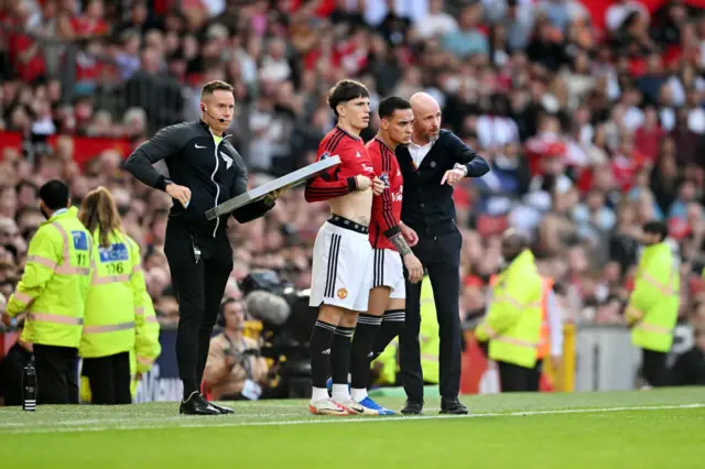 Garnacho and Antony stand on the touchline waiting to come on.