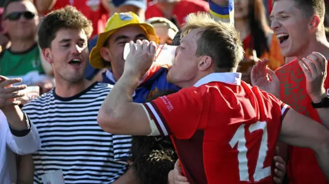 Nick Tompkins shares a drink with Wales fans at full-time