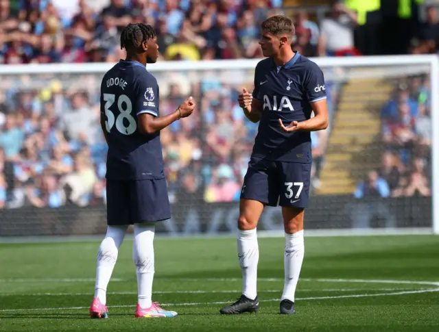 Udogie and van de Ven stand in conversation on the pitch.