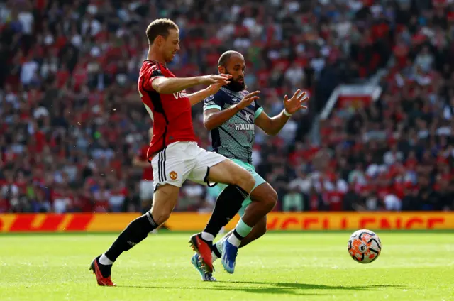 Evans tries to challenge Mbuemo for the ball.