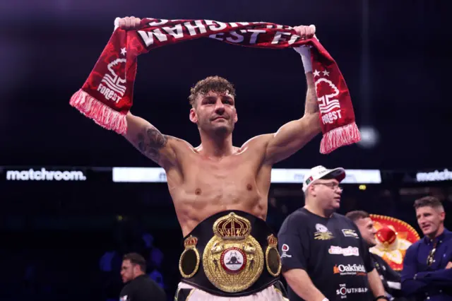 Leigh Wood holds up a Nottingham Forest scarf as he wears his WBA featherweight belt