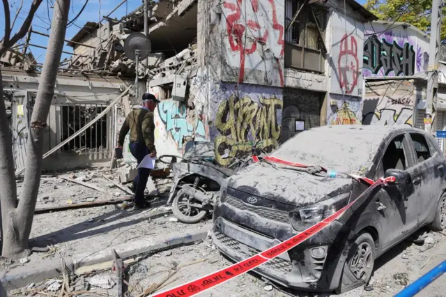 A man walks past a building destroyed in a rocket attack