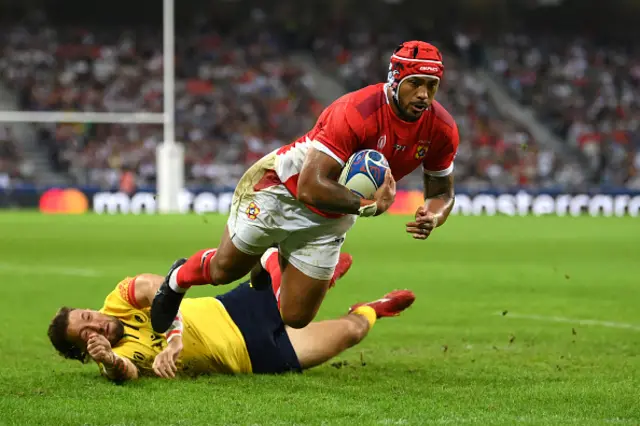 Pita Ahki of Tonga breaks through the tackle of Robert Irimescu