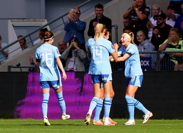 City players run to celebrate with Kelly after her goal.