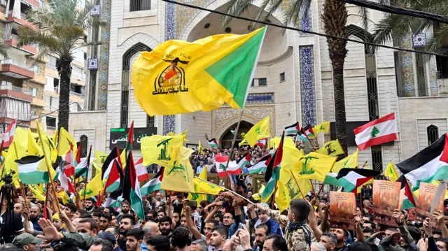 Supporters of Hezbollah wave Palestinian and Hezbollah flags during a rally, in Beirut