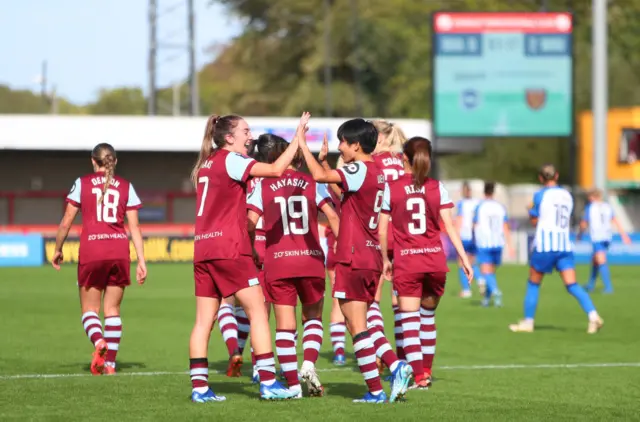 West Ham players celebrate and walk back to kick off as Brighton players stand forlorn in the background.