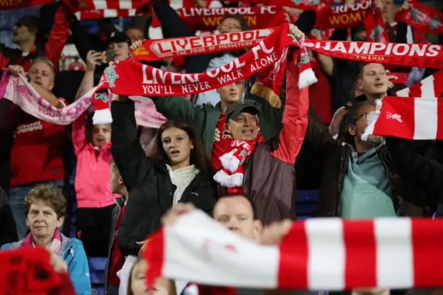 Liverpool fans hold their scarves aloft to sing the club anthem.