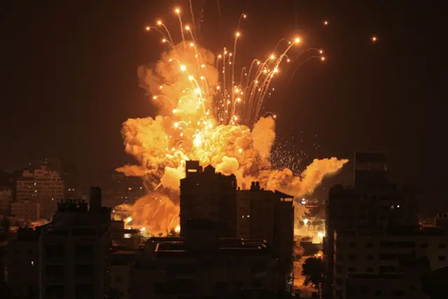 A night time shot shows a building being hit by a missile