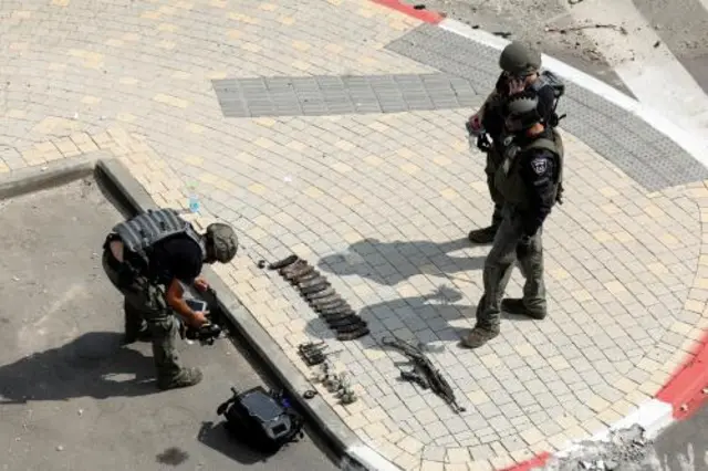 Israeli security gather near an arsenal of weapons near the site of a battle following a mass infiltration by Hamas gunmen from the Gaza Strip, in Sderot