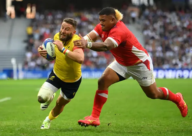 Florin Surugiu of Romania runs with the ball whilst under pressure from Siegfried Fisi'ihoi