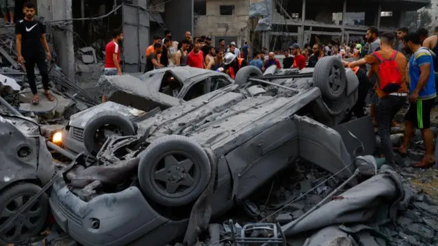 Palestinians look at burnt-out cars in the aftermath of Israel's strikes