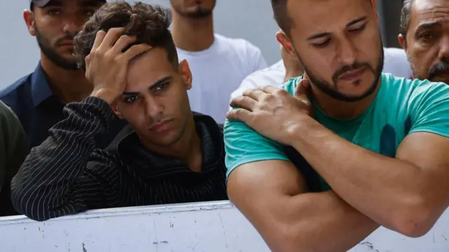 Men gather with relatives for funerals of the Shamalkh family