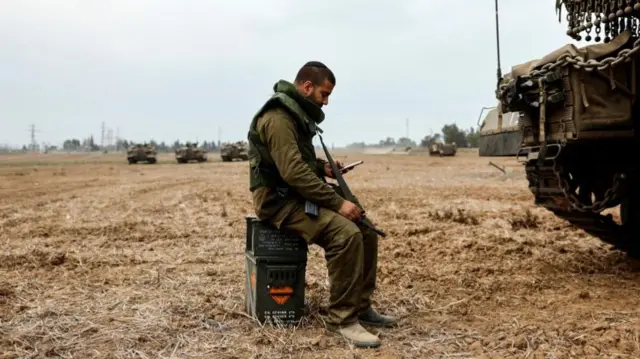 An Israeli soldier sits on a box of ammunition near the Gaza Strip