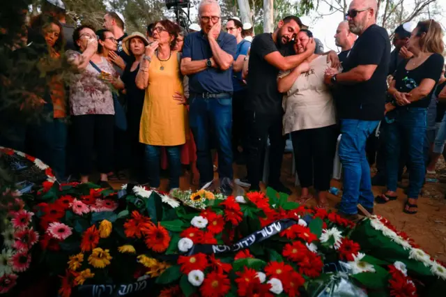 Mourners gather around the grave of an Israeli killed in the attacks