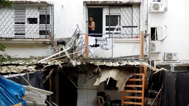 In Ashkelon, southern Israel, a man looks out his window at damage from Gazan rockets