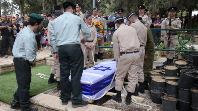 Soldiers lower the coffin into the grave