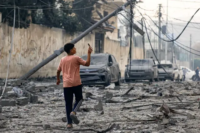 A young boy walks along a debris-strewn street in Gaza