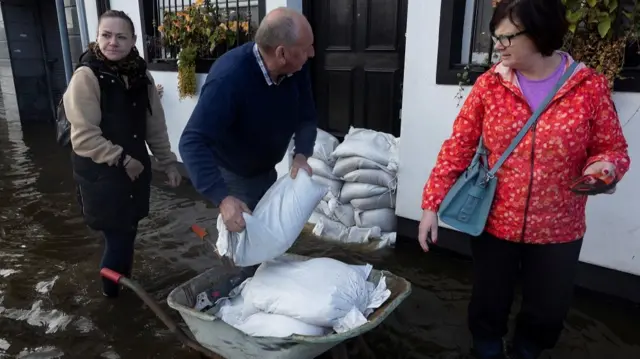 A man sandbags Magee's pub as water flows through streets after heavy rain caused extensive flooding, ahead of the arrival of Storm Ciaran, in the city centre of Newry, Northern Ireland,