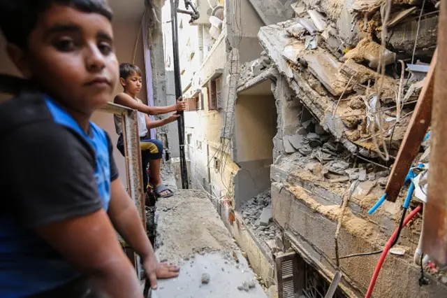 Children view buildings which were destroyed during Israeli air raids in the southern Gaza Strip overnight