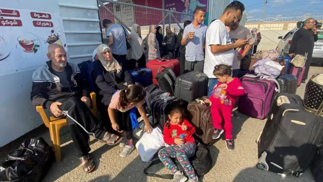 Palestinians with dual citizenship wait outside the Rafah border crossing with Egypt. It's thought injured Palestinians and foreign nationals will be allowed to leave today