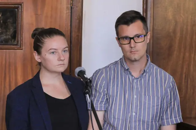 American couple, Nicholas Spencer (R) and his wife, Mackenzie Leigh (L), both 32, stand in the dock at Buganda road court charged with torturing ten-year-old John Kayima under their foster care in addittion to aggravated child trafficking, in Kampala, February 2, 2023. - The case was adjourned to June 10, 2022 as further investigations into the allegations are carried out by the state.