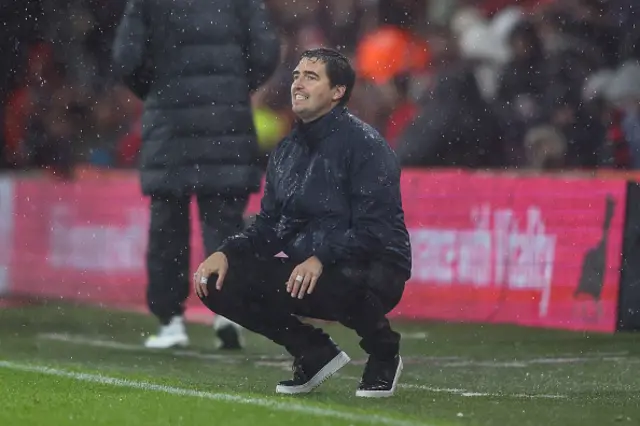 Andoni Iraola crouches down on the touchline