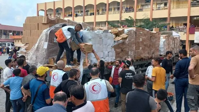 Members of the Palestine Red Crescent Society distribute aid to people in Khan Younis, in the southern Gaza Strip