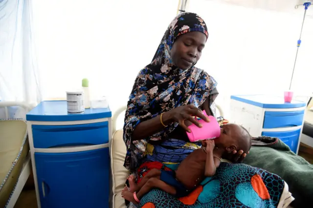 A woman feeds child of late sister suffering malnutrition in a clinic set up by health authorities in collaboraion with Medecins Sans Frontieres or Doctors Without Borders (MSF)in Katsina State, northwest Nigeria, on July 20, 2022.