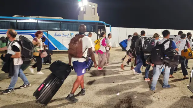 Several foreign nationals walk after passing the Rafah border crossing between the Gaza Strip and Egypt