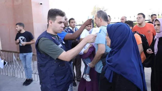 Man holds a temperature device to a woman's forehead.