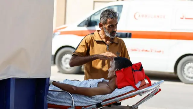 A man attends to a Palestinian, who will receive treatment in an Egyptian hospital, at the Rafah border crossing with Egypt, in the southern Gaza Strip, November 1, 2023.