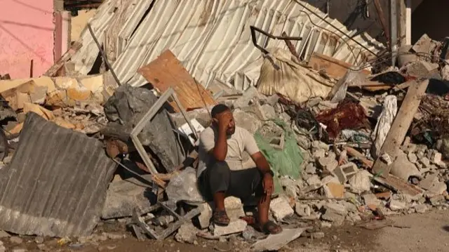 A Palestinian man sits on the debris of collapsed structures destroyed in the Israeli bombardment of Rafah