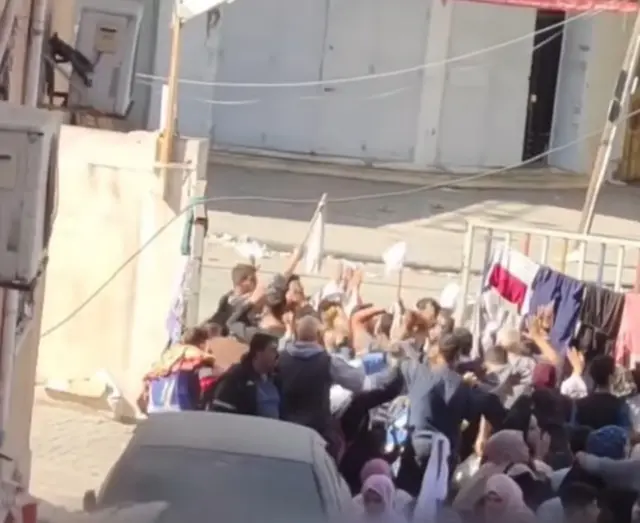 People wave white flags as they try to leave hospital