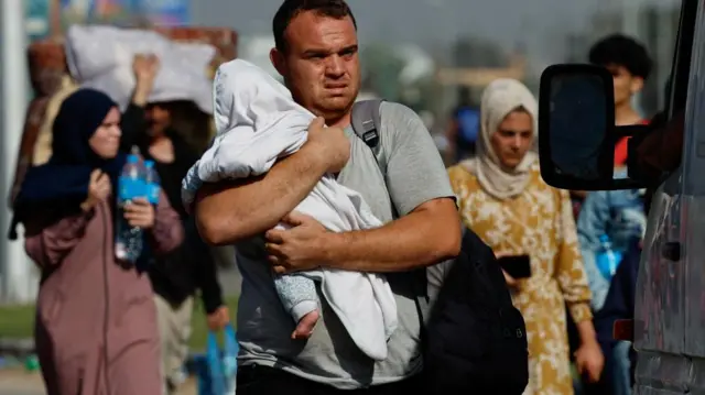 A man carries a child as Palestinians fleeing north Gaza walk towards the south