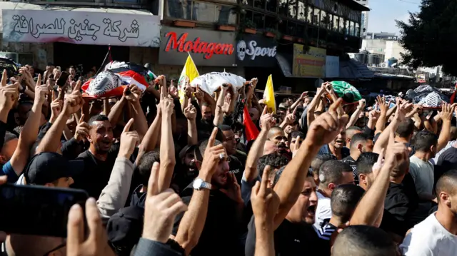 Mourners carry the bodies of 11 Palestinians who were killed in an Israeli raid in Jenin camp