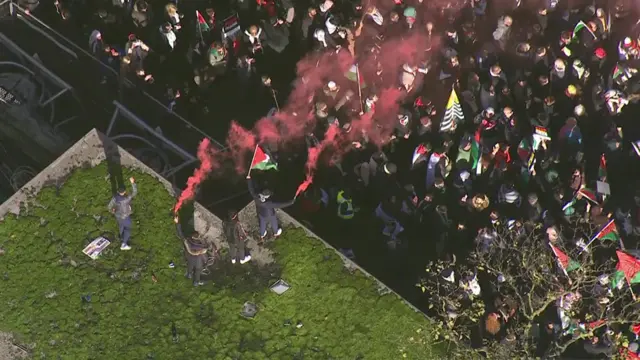 Pro-Palestinian protestors fire red smoke into the air
