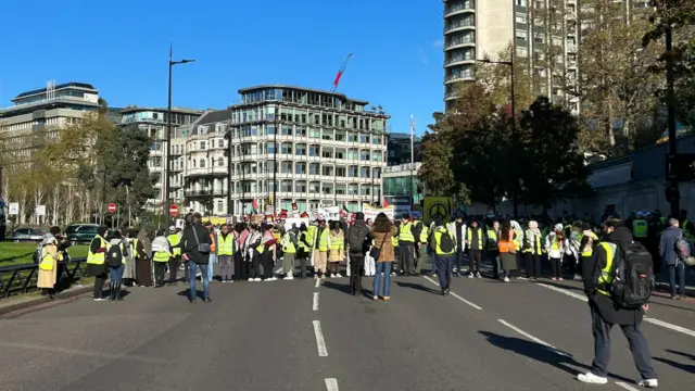 Protesters wearing high-vis jackets and holding placard gather in central London