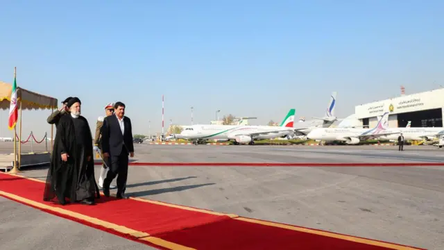 Iranian President Ebrahim Raisi walks on a red carpet at a Tehran airport before setting off for Saudi Arabia