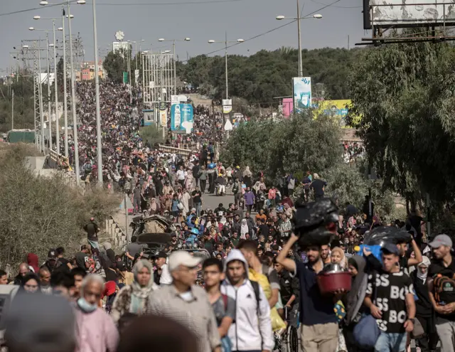 Hundreds of Palestinians evacuating to the south along a road, many are carrying belongings