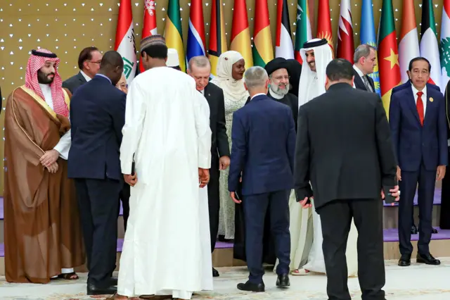 Several Arab and Islami leaders, including Saudi Arabia's Mohammed bin Salman, Iran's Ebrahim Raisi, Turkey's Recep Tayyip Erdogan and Qatar's Sheikh Tamim bin Hamad al Thani standing in front of several flags in Riyadh