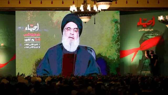 Hezbollah leader Hassan Nasrallah appears on a big screen in front of a crowd