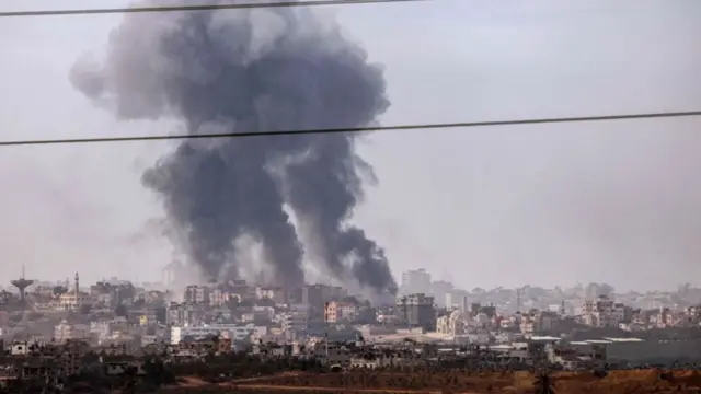 A plume of smoke hanging above buildings in the Gaza Strip
