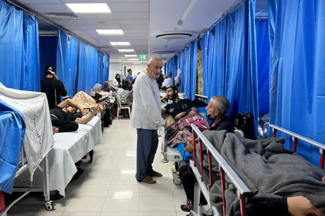 A man wanders among hospital patients lying on beds in Gaza's Al-Shifa hospital