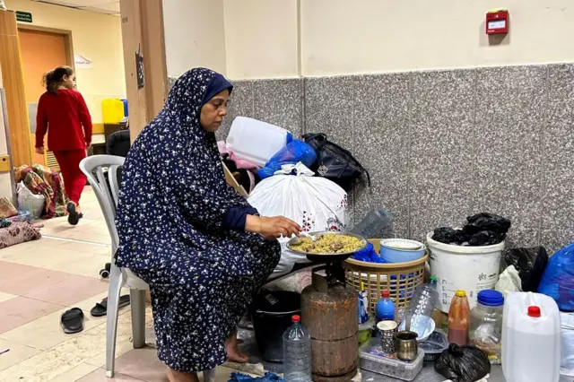A woman cooks over a makeshift stove at Al-Shifa hospital in Gaza
