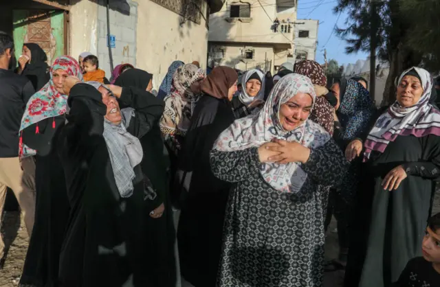Women weep as they walk through the street