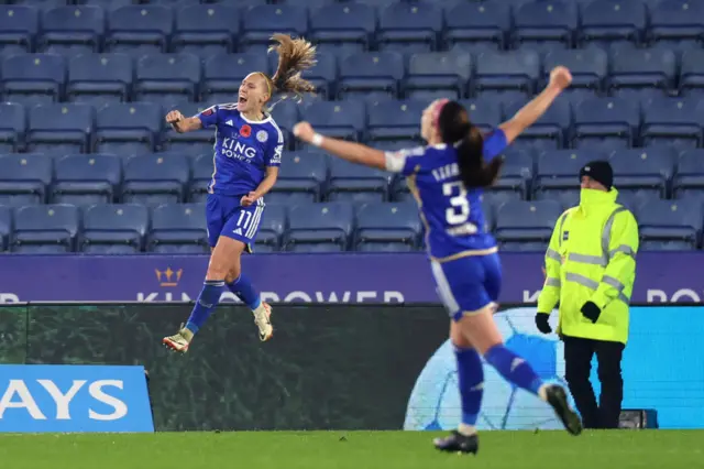 Cayman jumps and punches the air in delight to celebrate her goal.