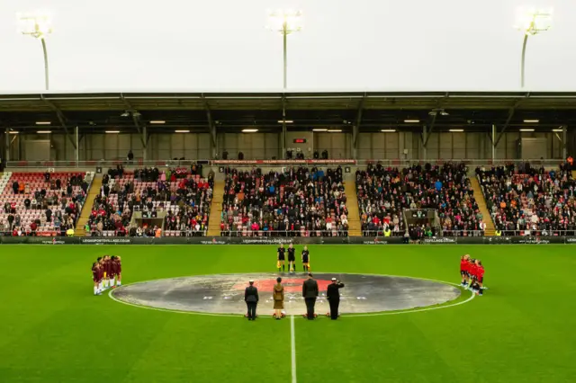 Fans, players and members of the armed forces gather for a moment's silence.